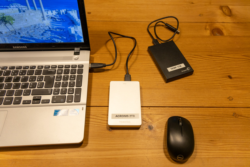 Disque dur USB 2,5" connecté à un ordinateur portable, à côté d'un autre disque dur et d'une souris sans fil